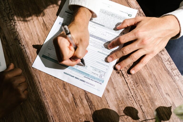 Person filling out a personal loan application form on a wooden table