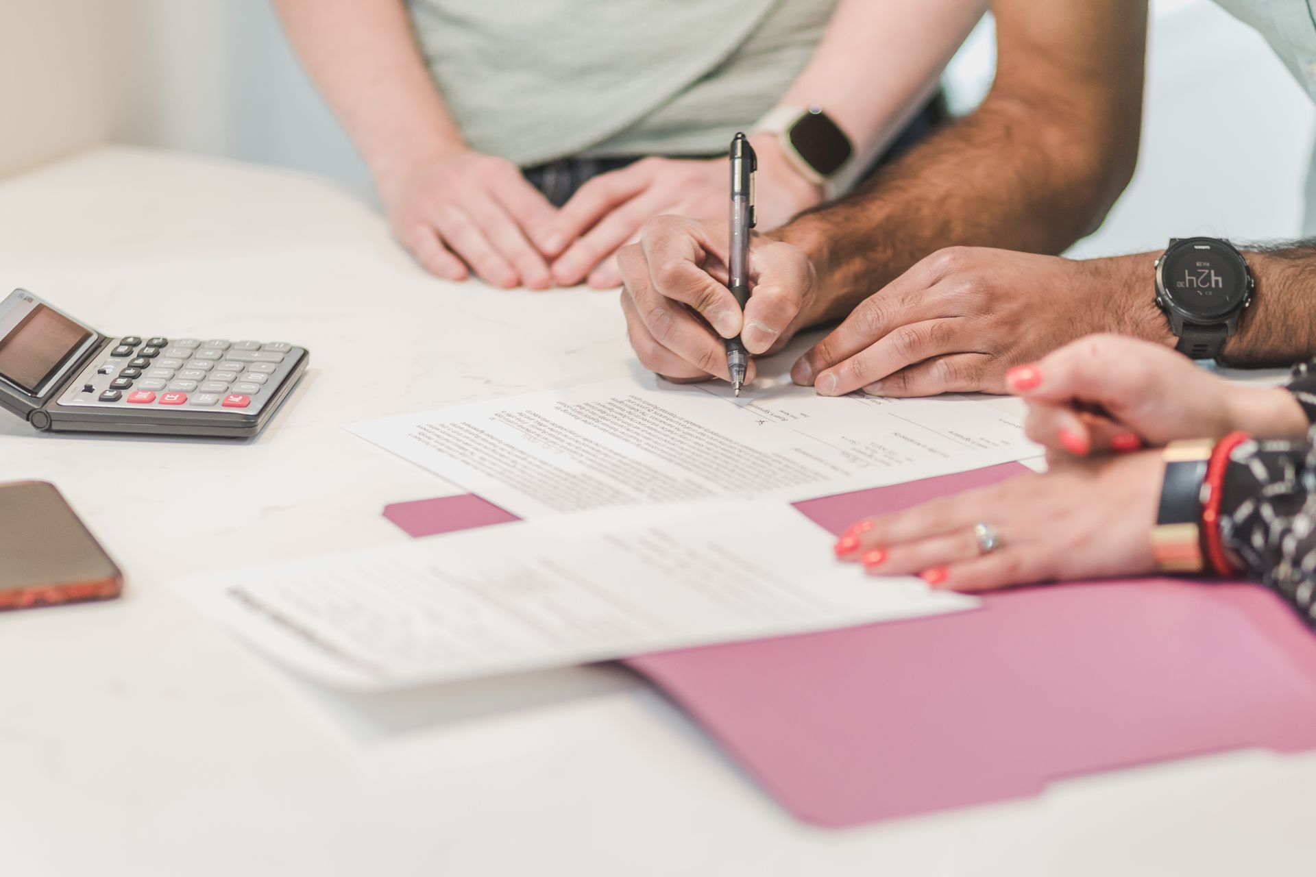 Borrower reviewing loan paperwork with a calculator on a white table