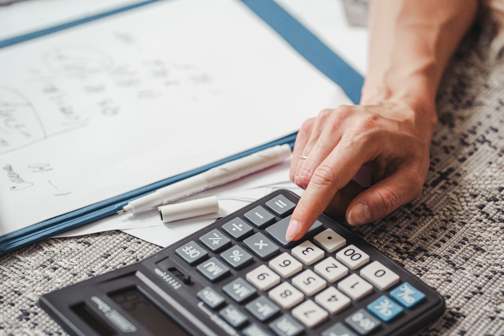 A hand using a calculator on top of financial documents