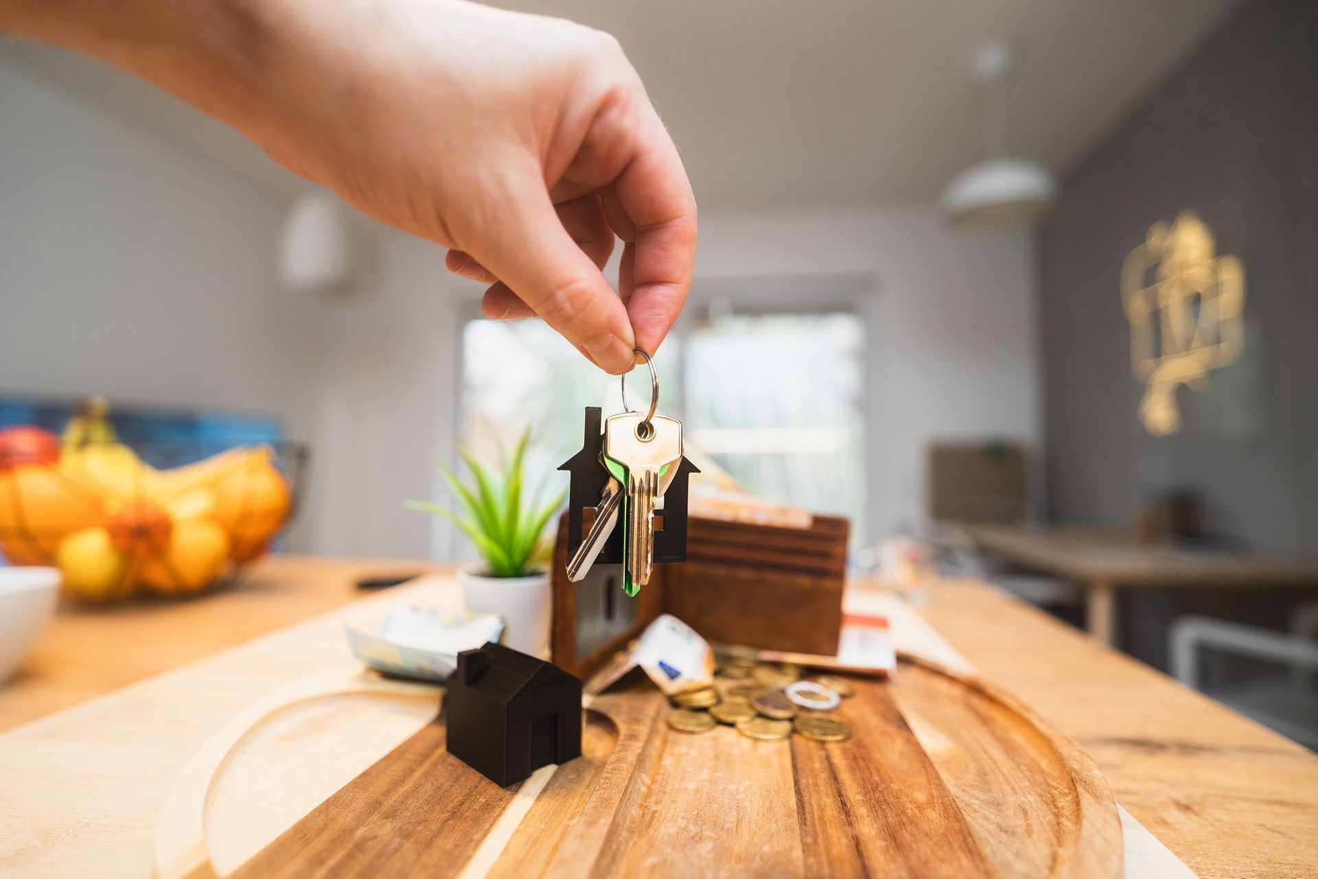 Hand holding keys in a modern living room setting, symbolizing home ownership