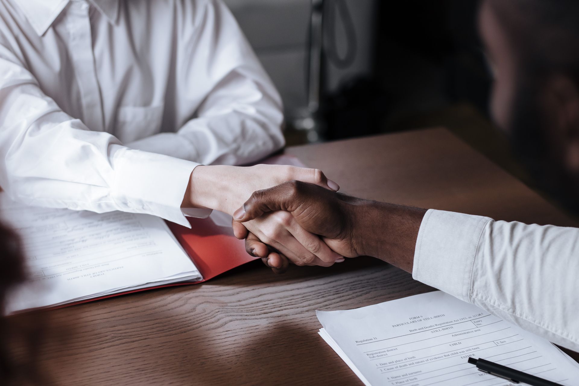 Close-up of a diverse business handshake over documents, symbolizing agreement