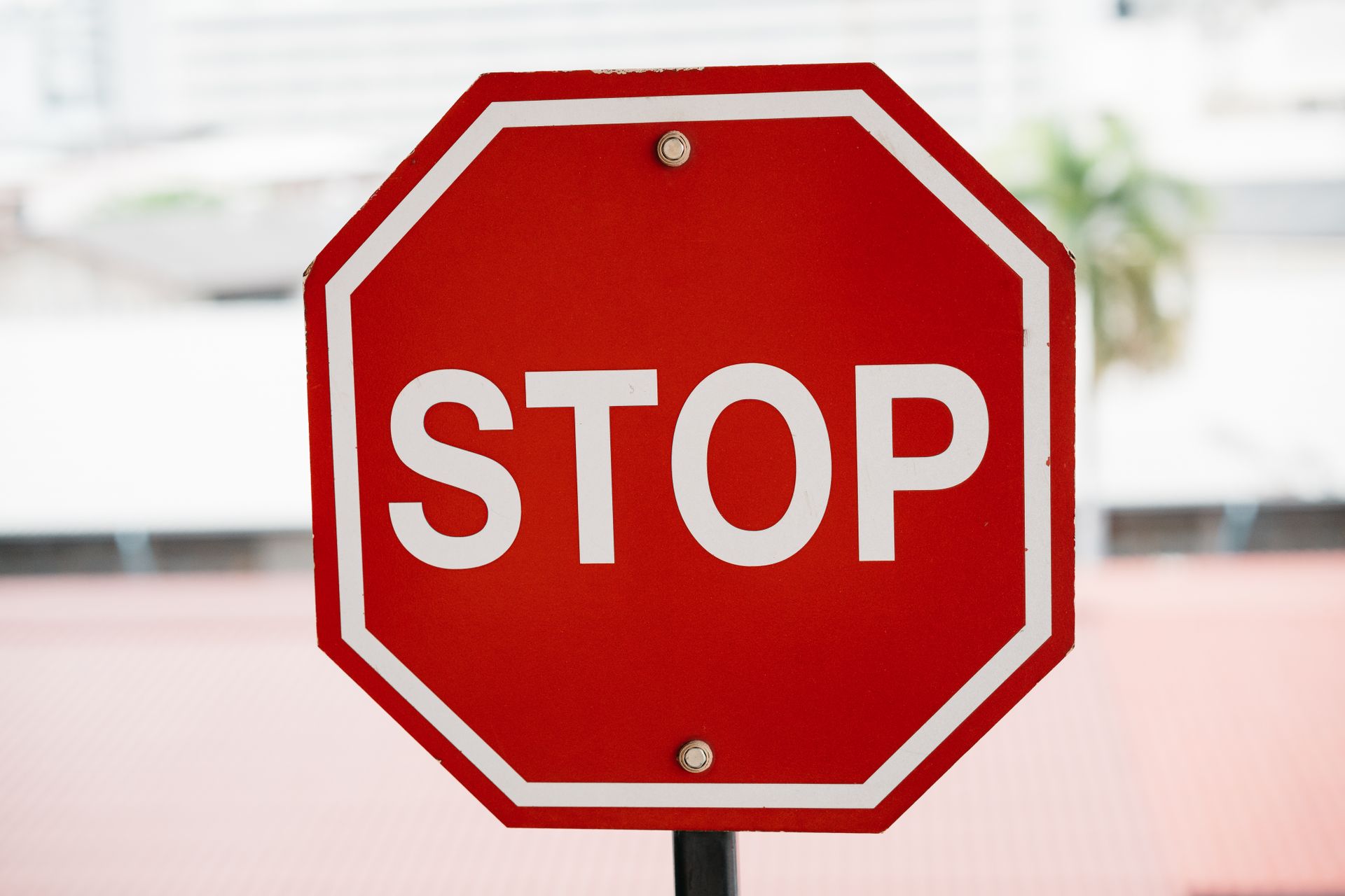 A red stop sign with bold white text in an urban setting, signaling caution