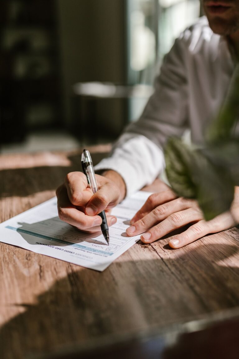 Borrower filling out loan application paperwork with a pen