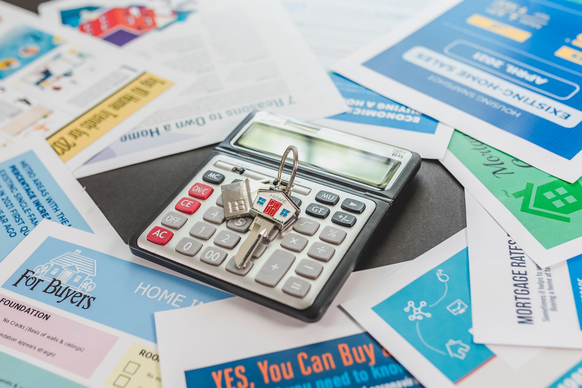 Calculator and real estate flyers depicting financial planning for home buyers