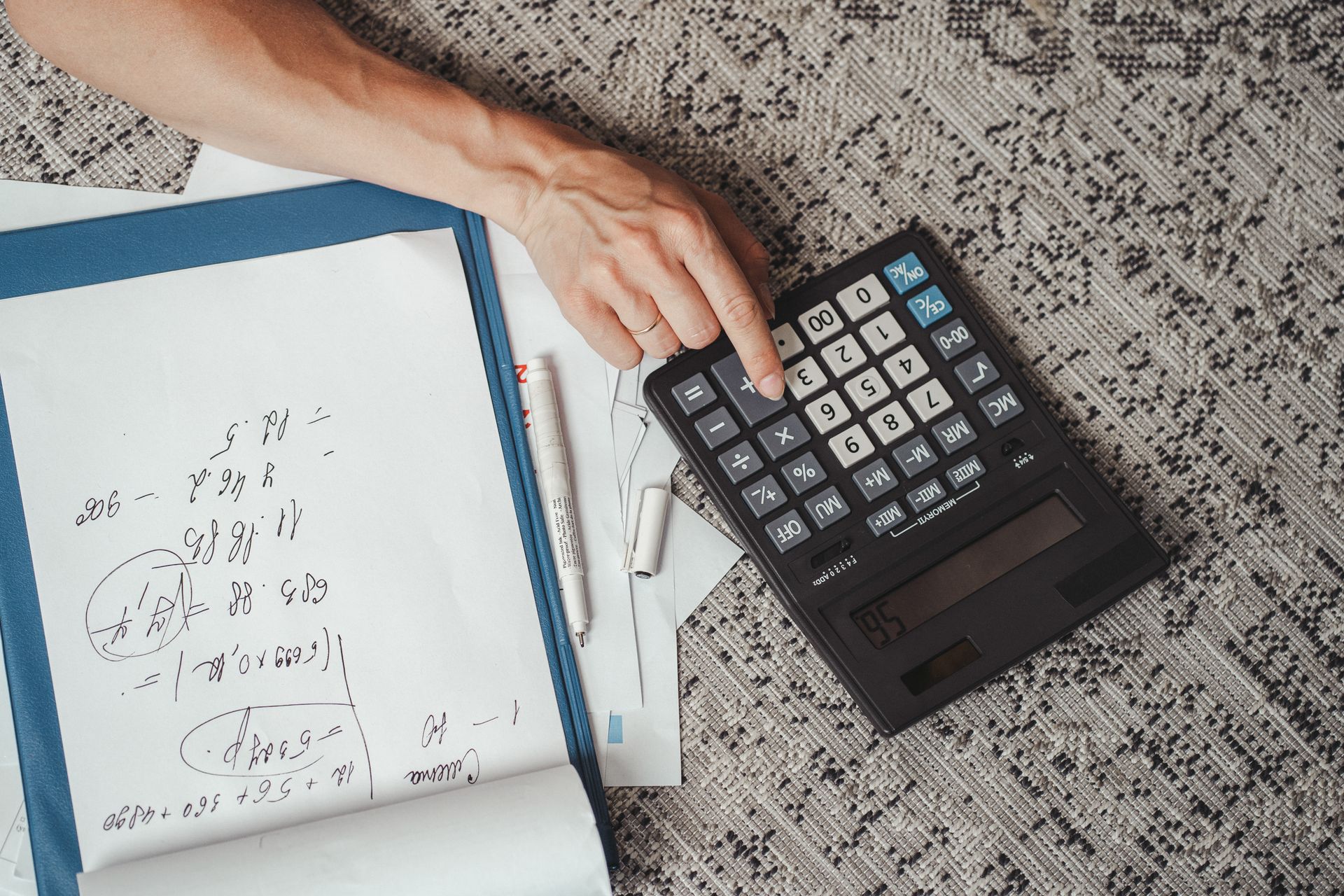 Person doing financial calculations with calculator and notebook