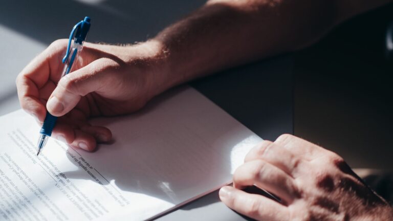 Close-up of a hand signing mortgage documents with a pen