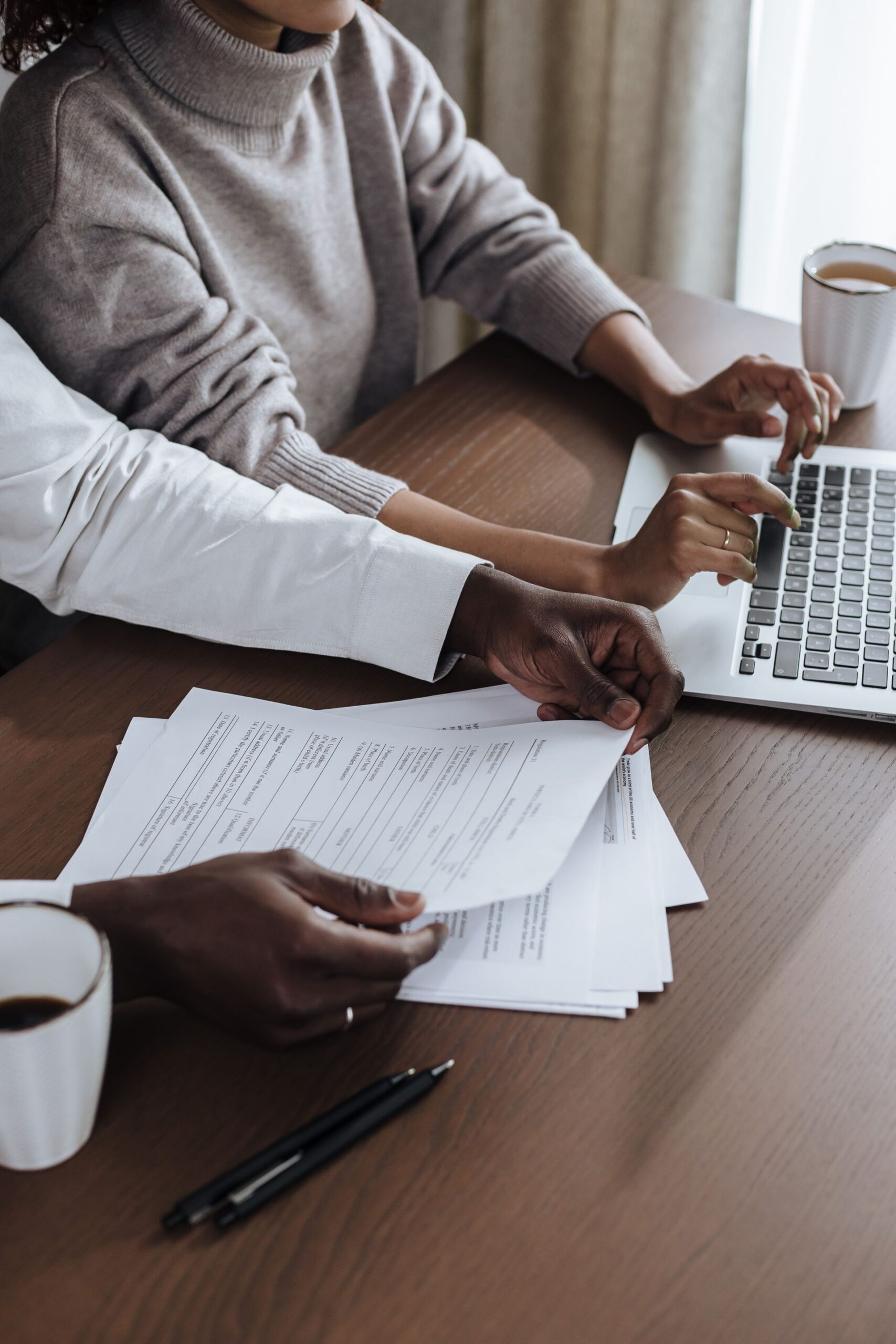Two people reviewing and comparing loan documents with a laptop