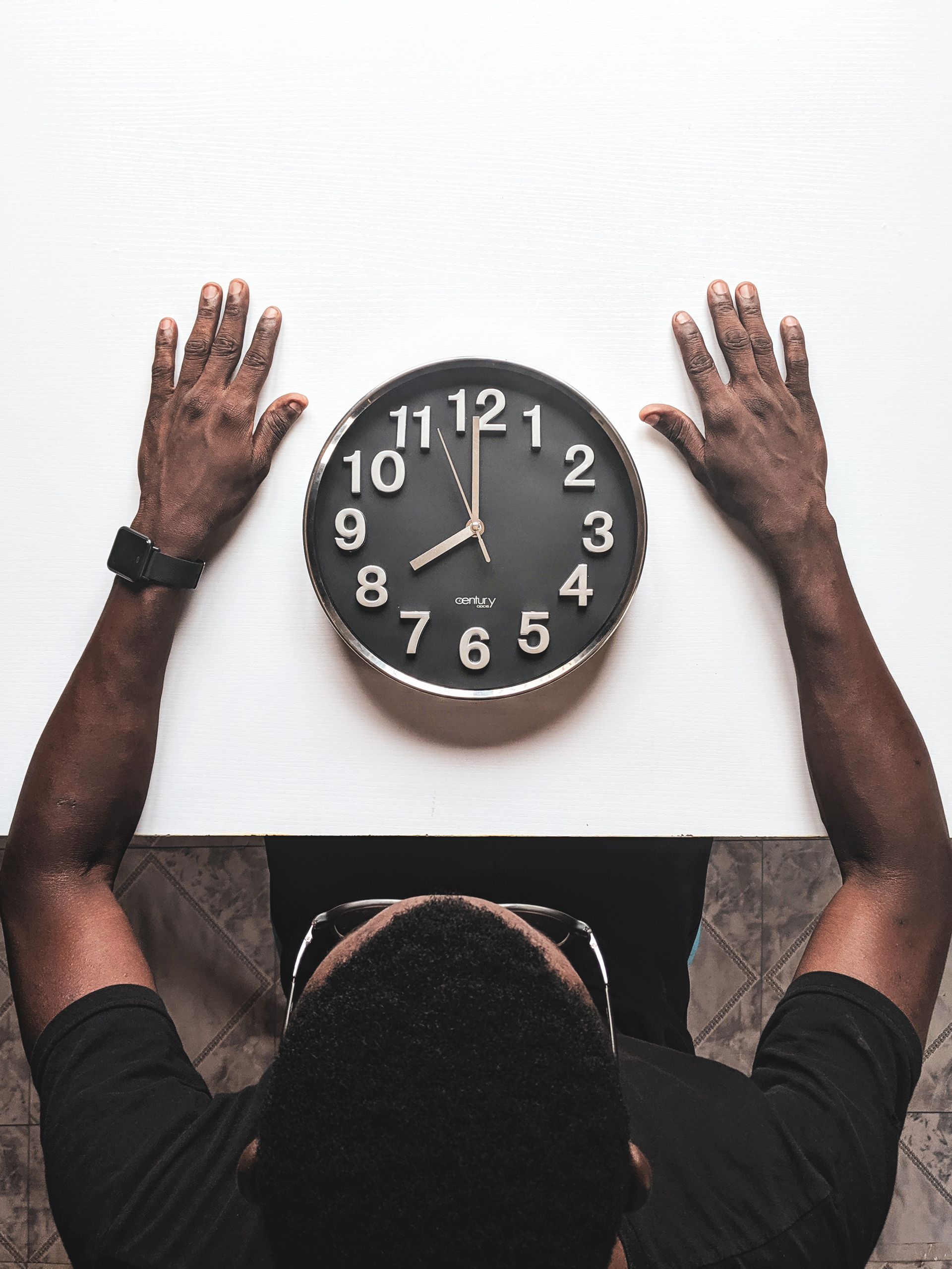 Person looking at a wall clock while waiting