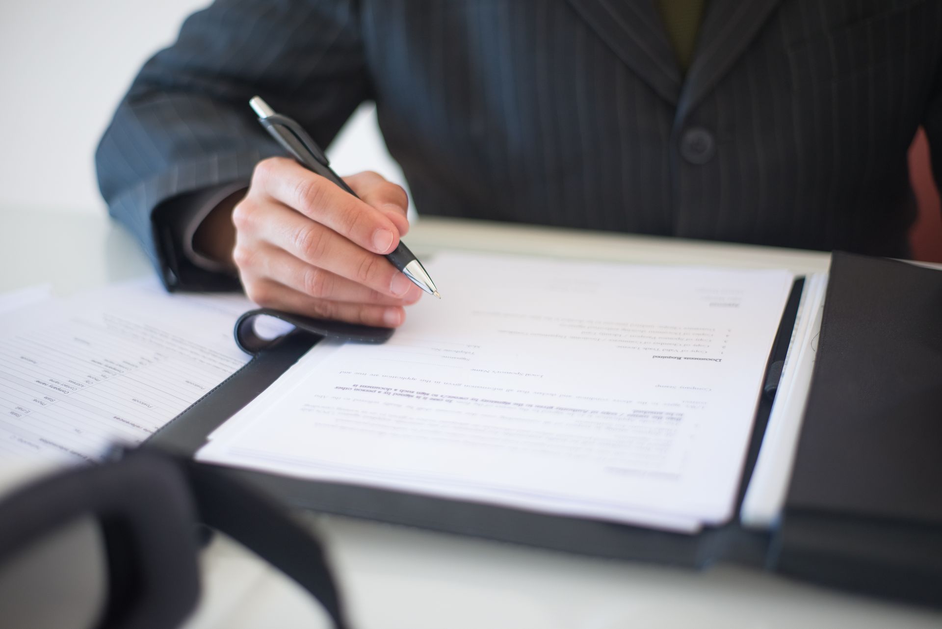 Close-up of a hand signing loan documents with a pen