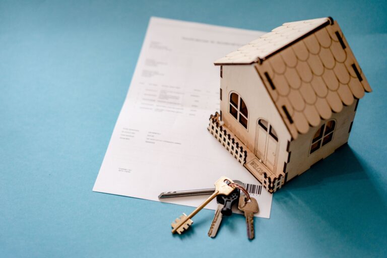 Miniature wooden house with keys and a contract symbolizing a home purchase
