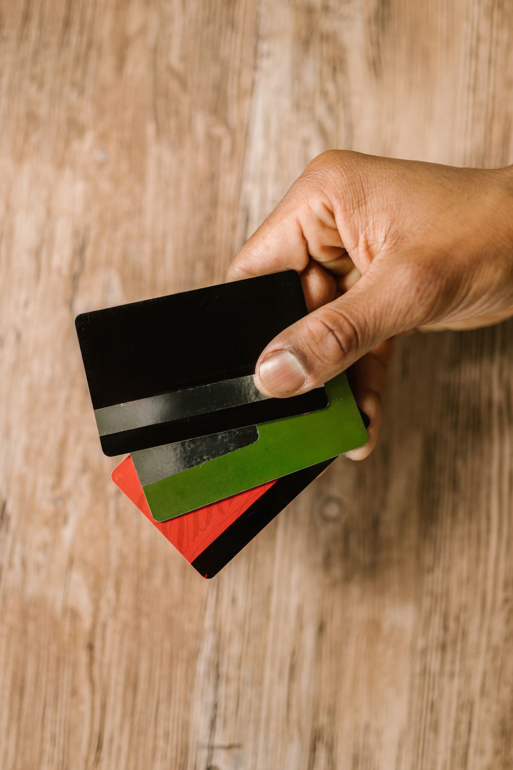 Hand holding multiple credit cards on a wooden background