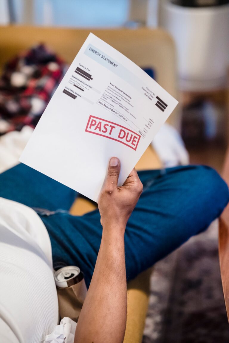 Man holding a past-due billing statement expressing financial stress