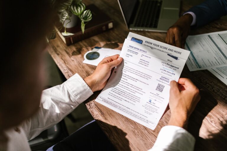 Man examining a financial document at a wooden desk