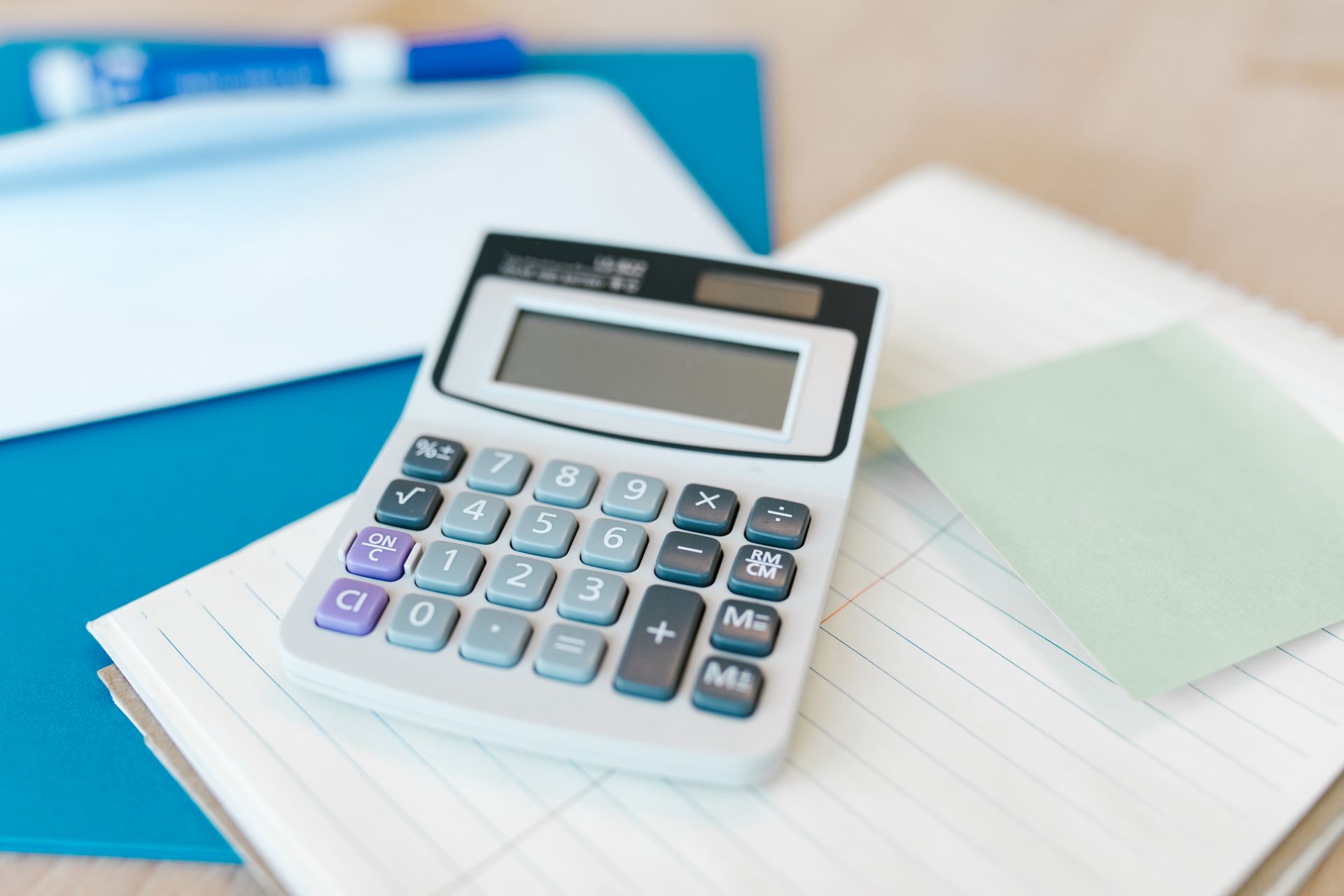 White calculator on a stack of lined paper in an office