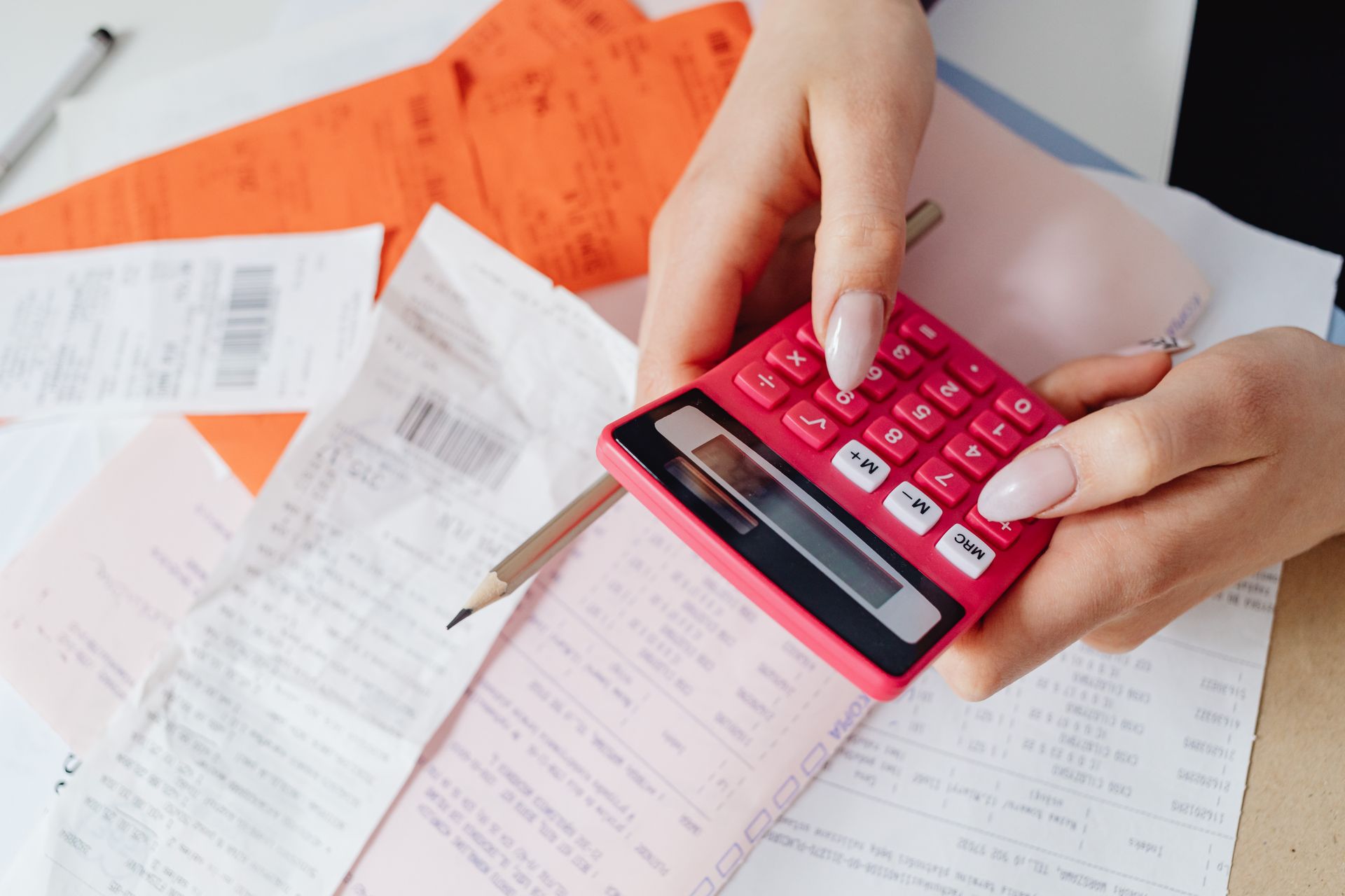 Hands using a calculator to manage expenses and receipts
