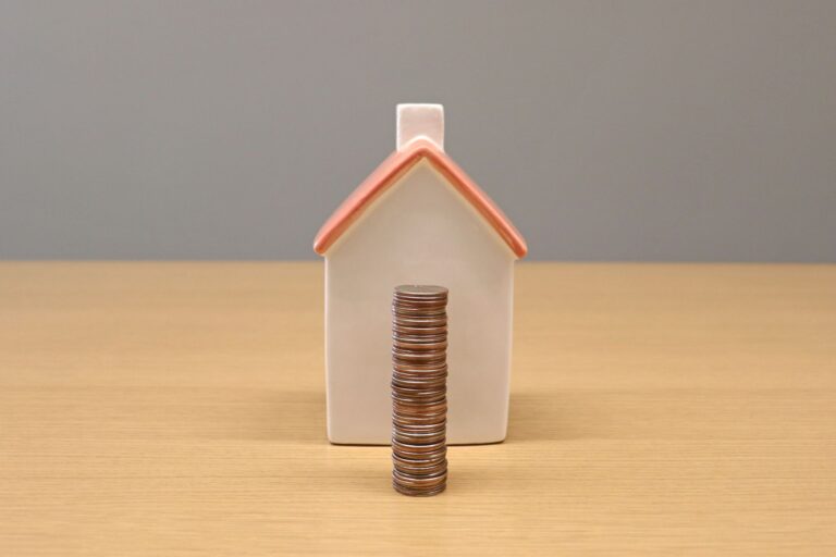 Stack of coins in front of a porcelain house symbolizing equity