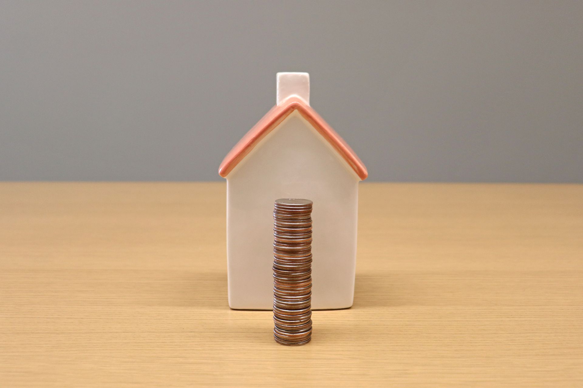 Stack of coins in front of a porcelain house symbolizing equity