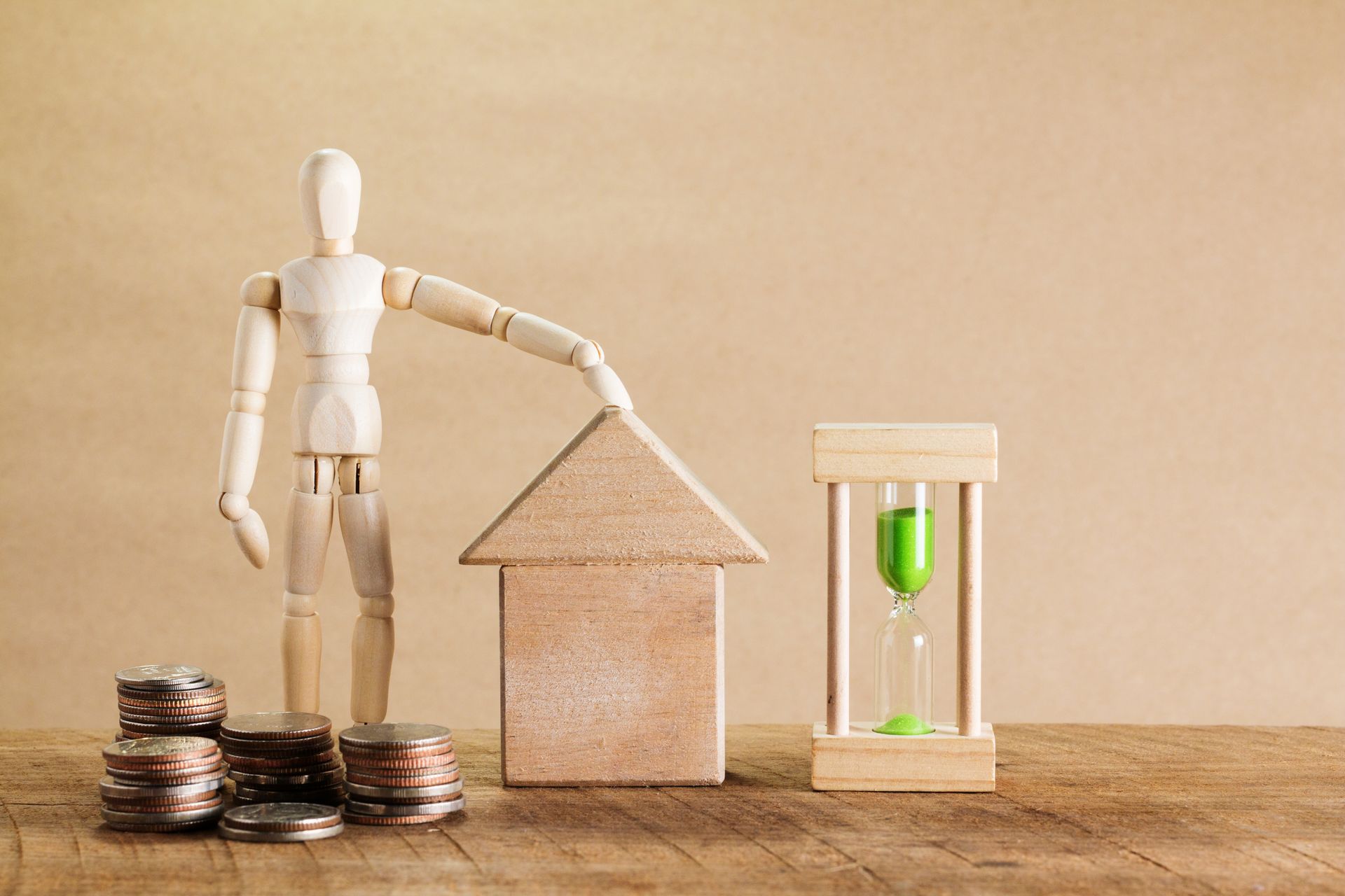 Wooden mannequin with a house model, coins, and hourglass