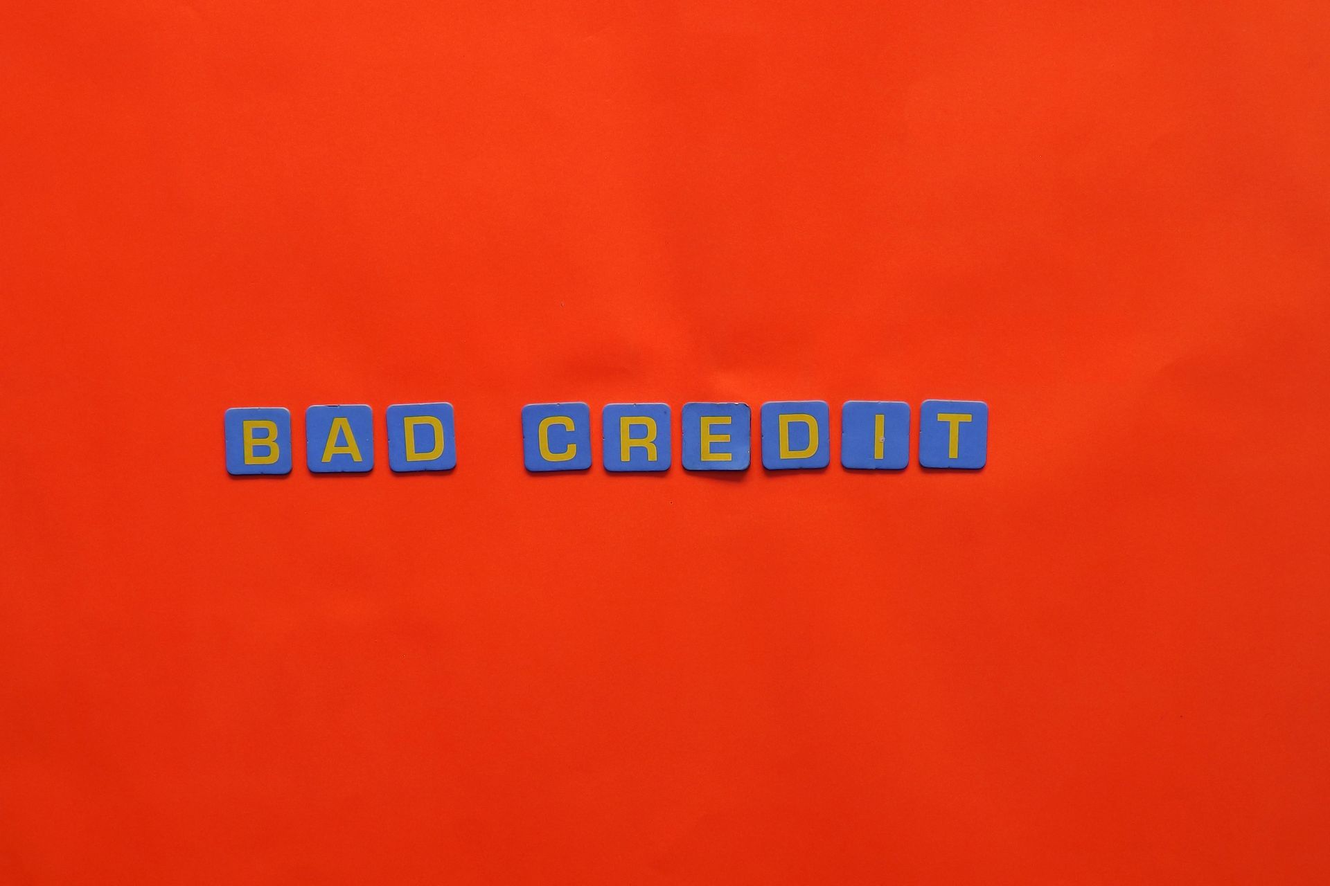 Letter blocks spelling bad credit on an orange background