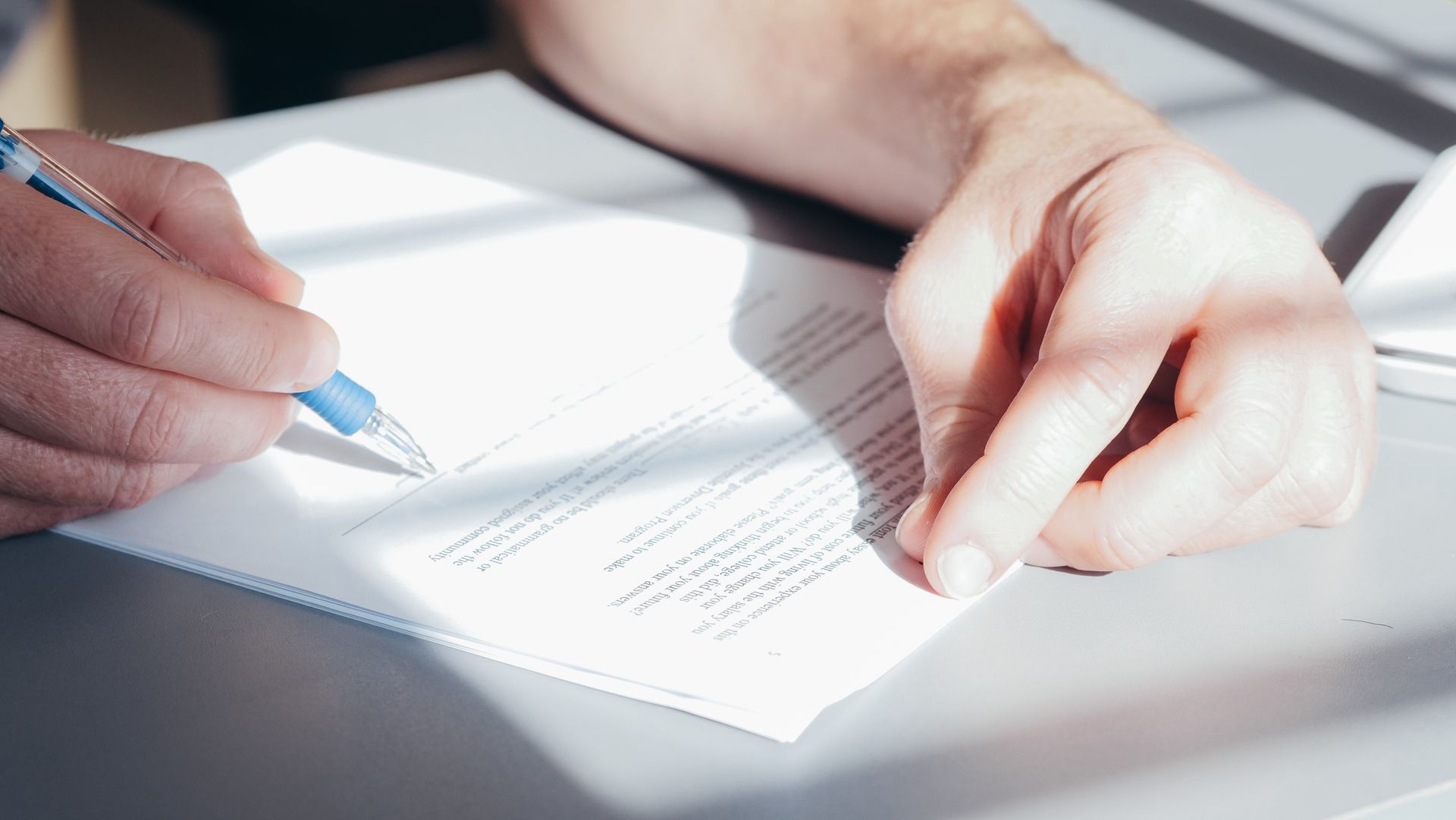 Hands signing a contract with a blue pen