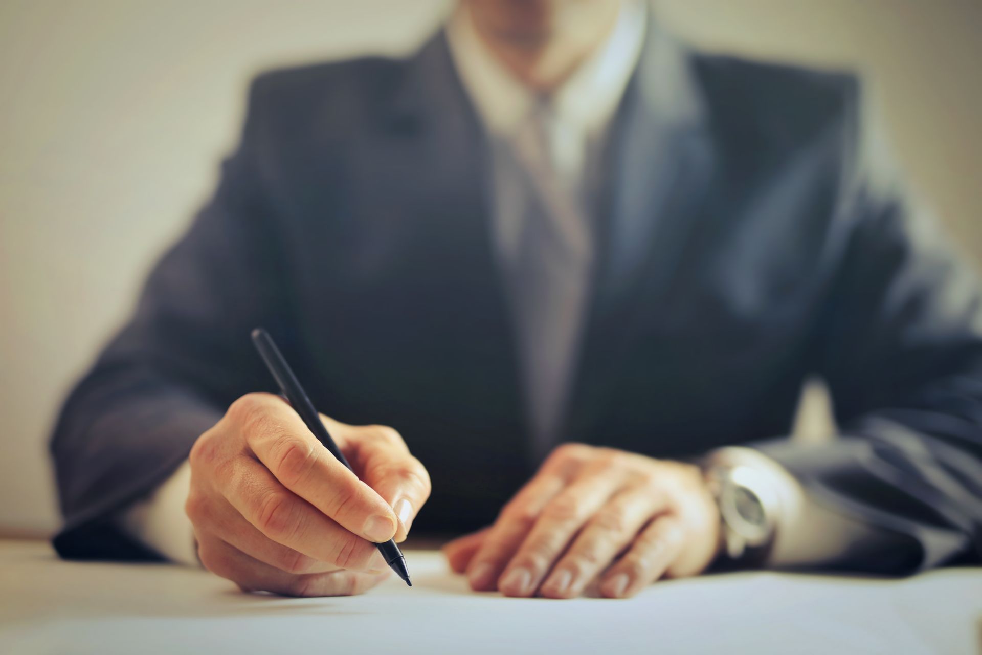 Businessman in a suit signing a contract at an office desk