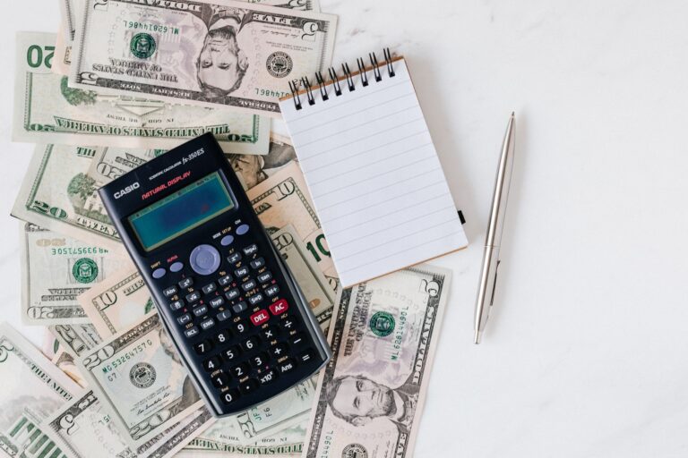 Flat lay of dollar bills with a calculator and notebook for budgeting