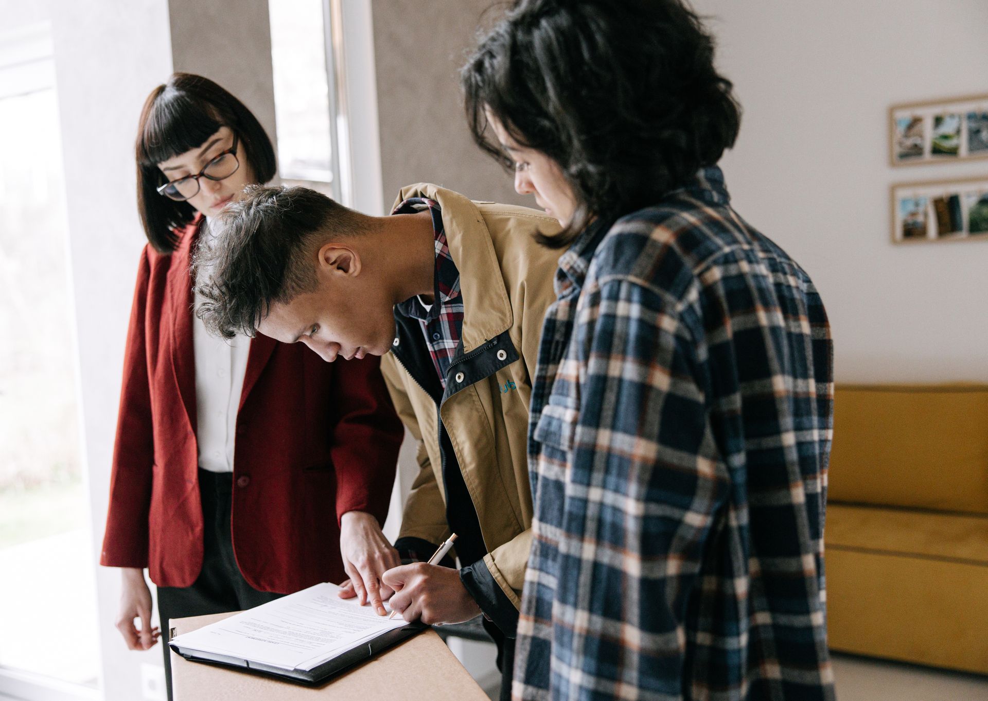 Young couple signing a real estate agreement with an agent at a table