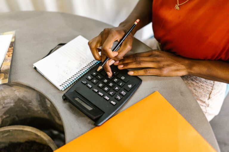 Woman using a calculator and notepad to work out a household budget