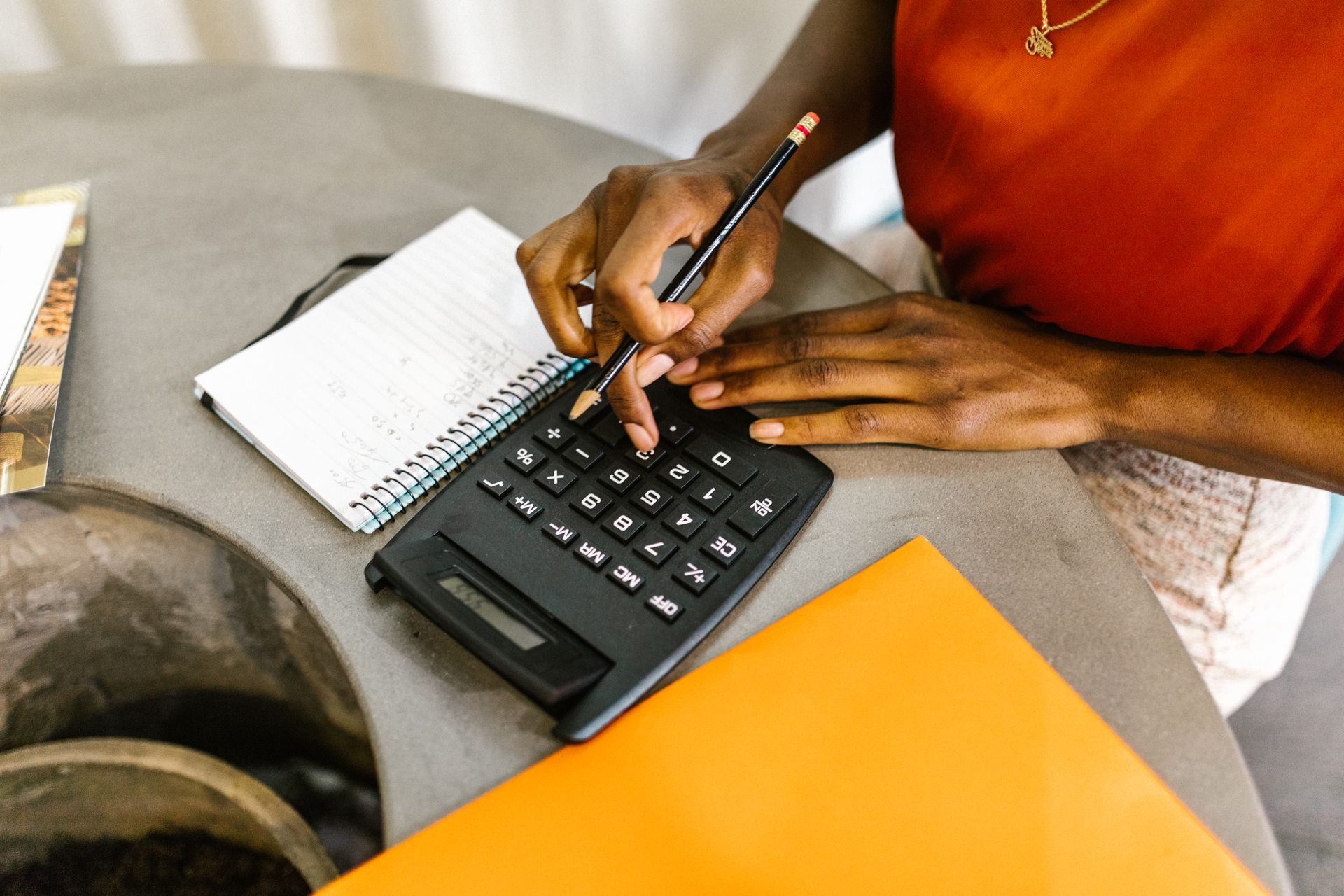 Woman using a calculator and notepad to work out a household budget