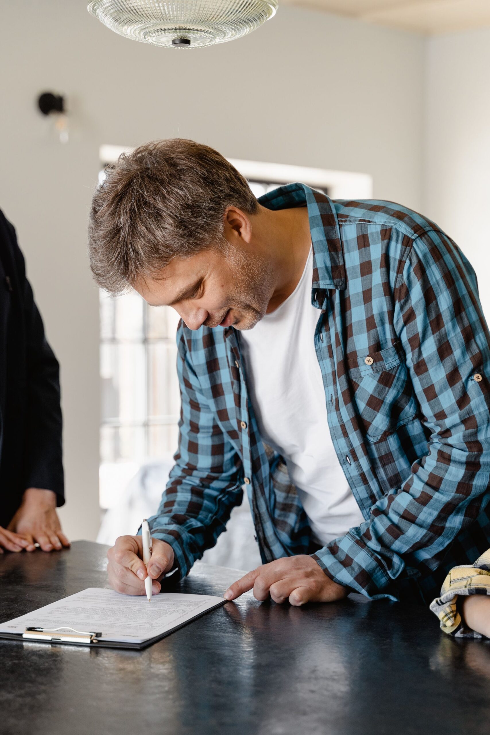 A man signing important papers in a home setting