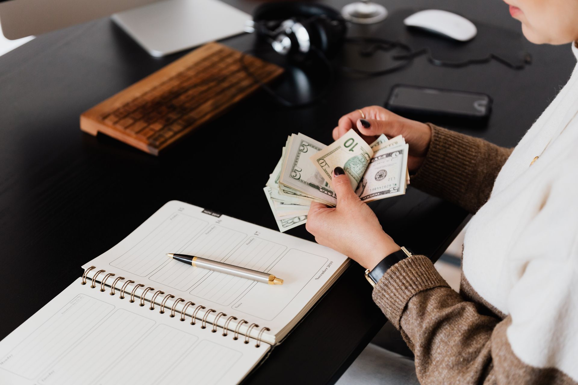Business owner counting cash at a desk with a planner