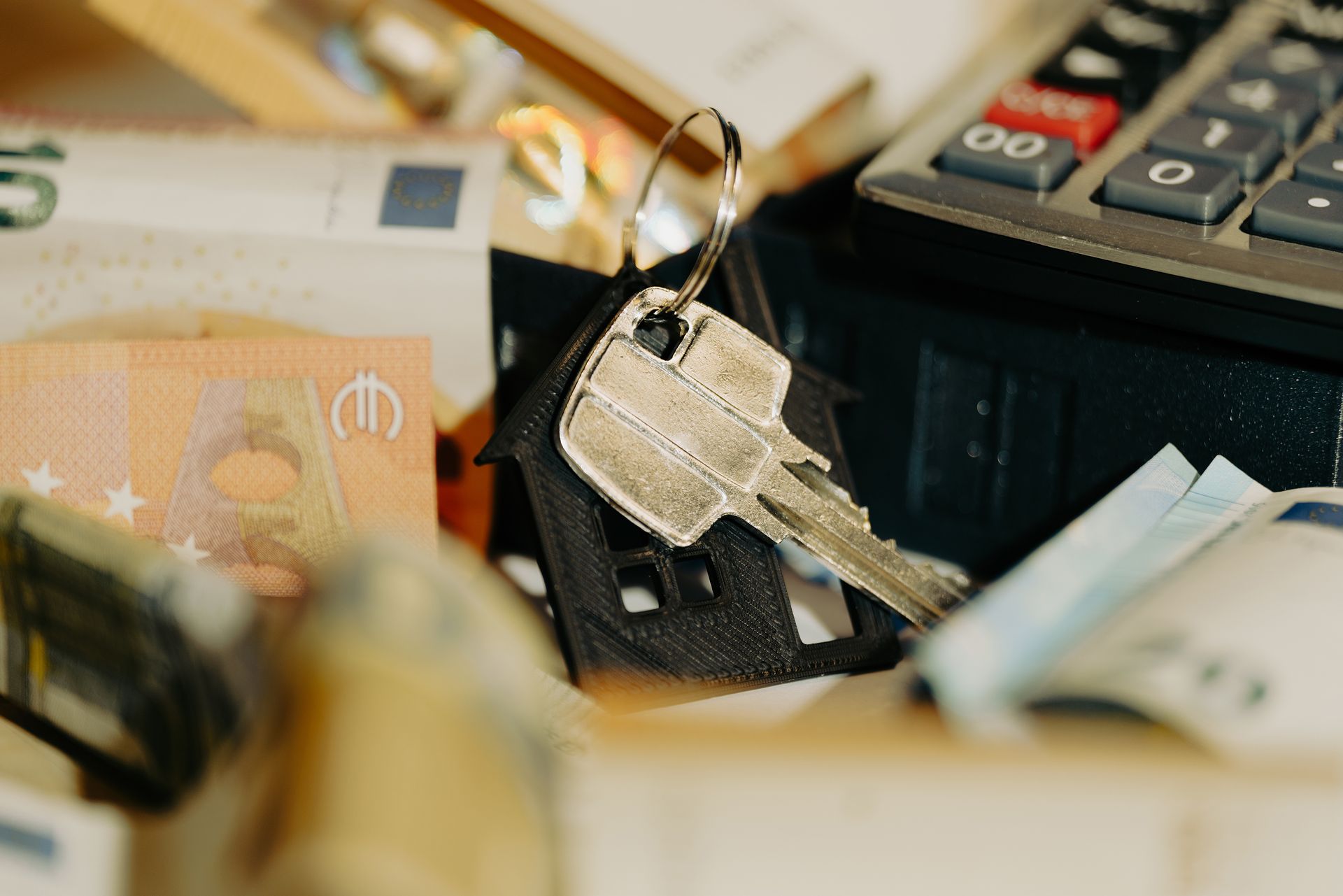 House keys on a keychain with euro banknotes and a calculator, symbolizing real estate investment