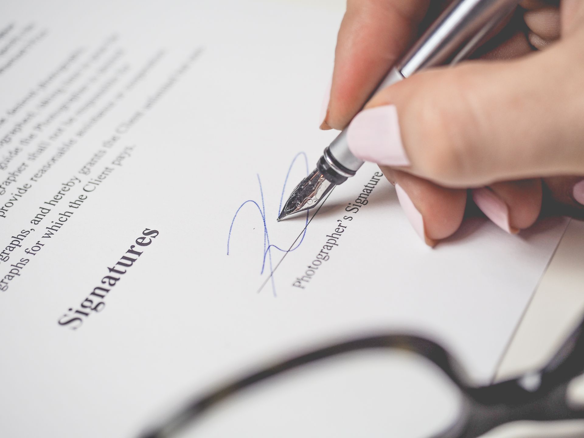 Close-up of a hand signing a contract with a silver pen