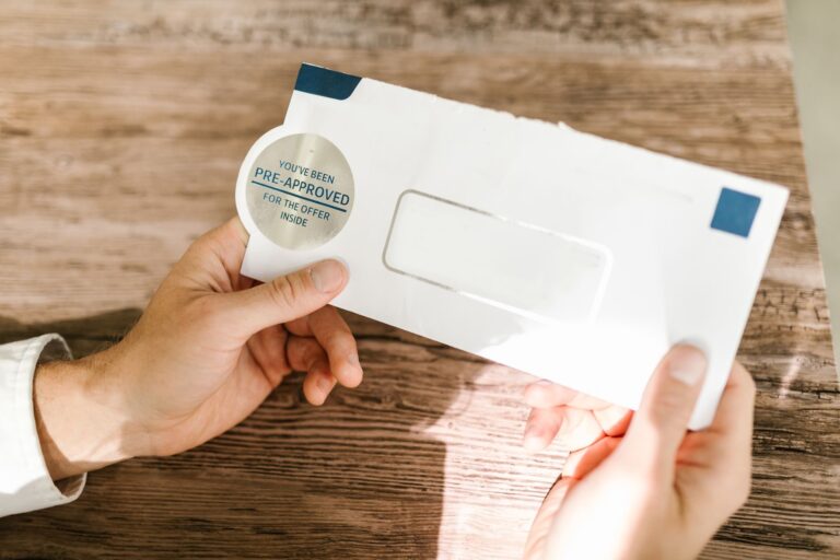 Hands holding a pre-approved mortgage offer envelope on a wooden table