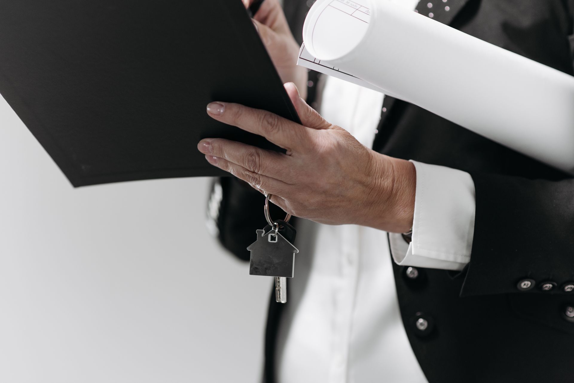 Close-up of a business professional holding a house key and architectural plans